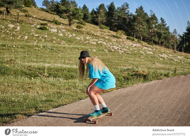 Woman riding skateboard along road in mountains skater woman ride hipster summer young weekend female rural sport hobby style freedom activity enjoy carefree