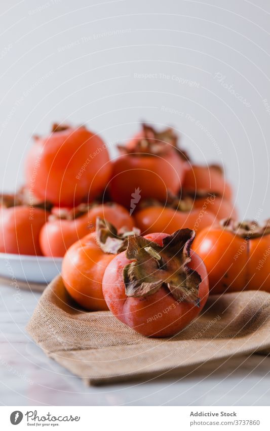 Ripe persimmons on plate in kitchen fruit sweet pile fresh vitamin diet nutrition nutrient delicious bright table healthy heap natural food healthy food organic