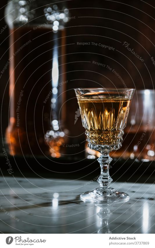 Glass of alcohol beverage on marble table whiskey bar glass drink bottle serve counter booze refreshment pub transparent modern style cold event celebrate