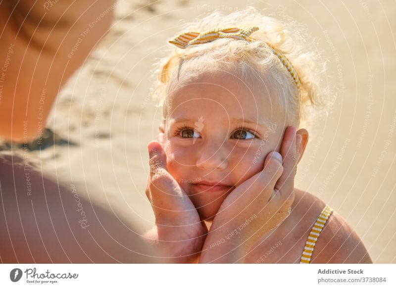 Hands wrapped around the face of a little girl with an expression of admiration on a beach embrace tan share talk togetherness bonding brother harmony stand