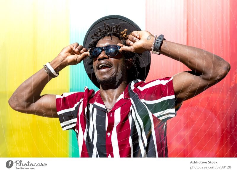 Stylish ethnic man in sunglasses and hat style fashion trendy colorful stripe young modern male african american black hipster multicolored confident accessory