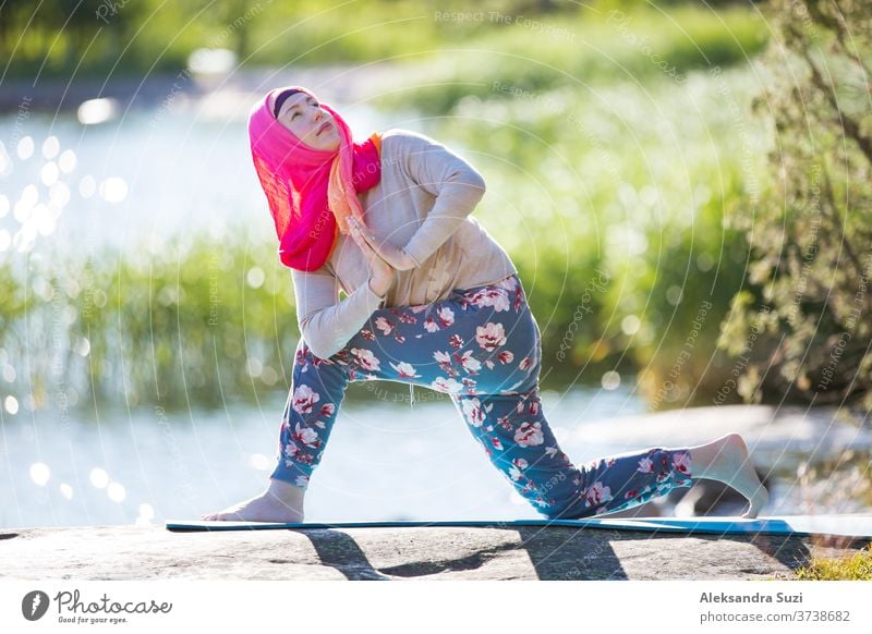 Attractive woman in hijab training in the park, meditating. Doing yoga exercises on fresh air and enjoying early morning. Healthy lifestyle activity adult asana