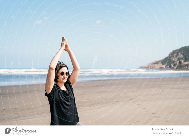 Young woman in balancing yoga asana standing on beach sea practice pose tree vrksasana balance calm seashore harmony wellness lifestyle female nature vitality