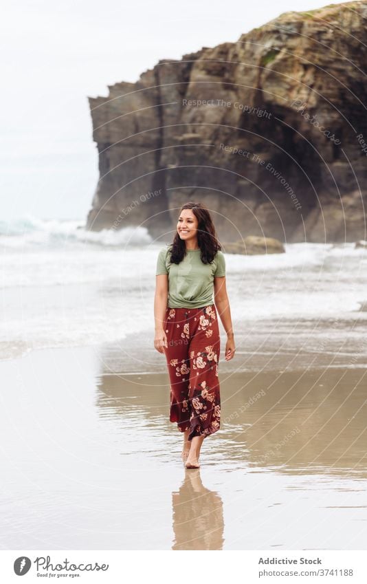 Smiling woman on beach in summer wet seashore walk water cliff seaside female relax travel tourism traveler coast ocean rocky nature happy vacation lady holiday