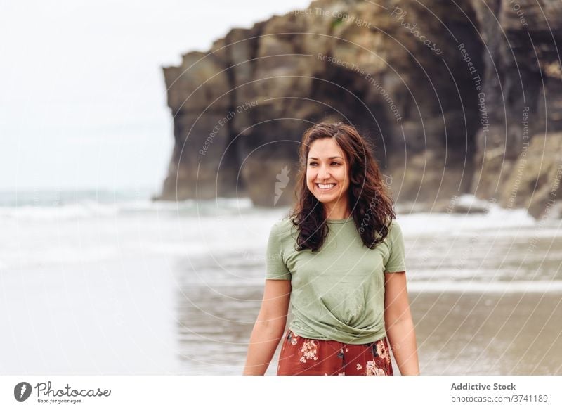 Smiling woman on beach in summer wet seashore walk water cliff seaside female relax travel tourism traveler coast ocean rocky nature happy vacation lady holiday