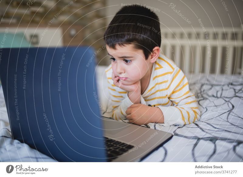 Little kid using laptop at home little gadget boy browsing bedroom child surfing internet addict device online lifestyle male preschool connection focus watch