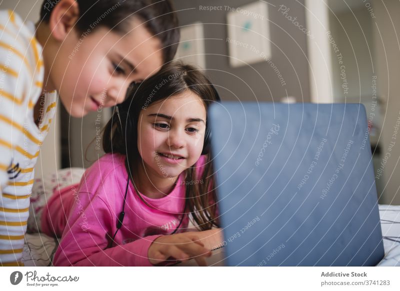 Cheerful kids using laptop in bedroom sister and brother home sibling together little gadget cheerful play happy children contemporary having fun browsing