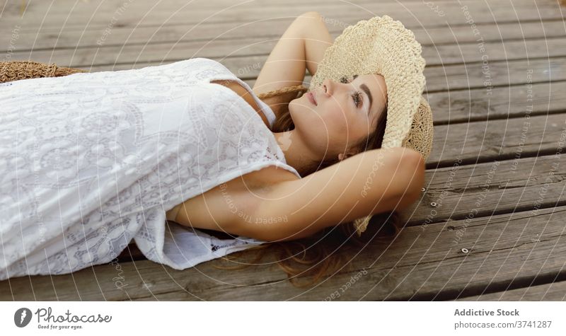 Carefree woman resting on pier in summer carefree dreamy daydream wooden lying relax freedom female dress sunhat quay countryside happy joy cheerful romantic
