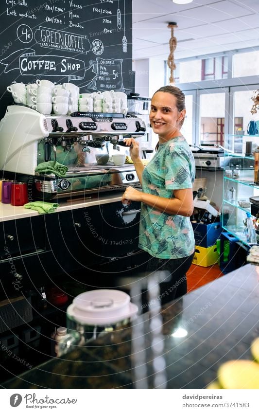 Female barista preparing coffee machine woman coffee shop coffee maker happy looking camera waitress cup cafeteria drink dishcloth business job professional