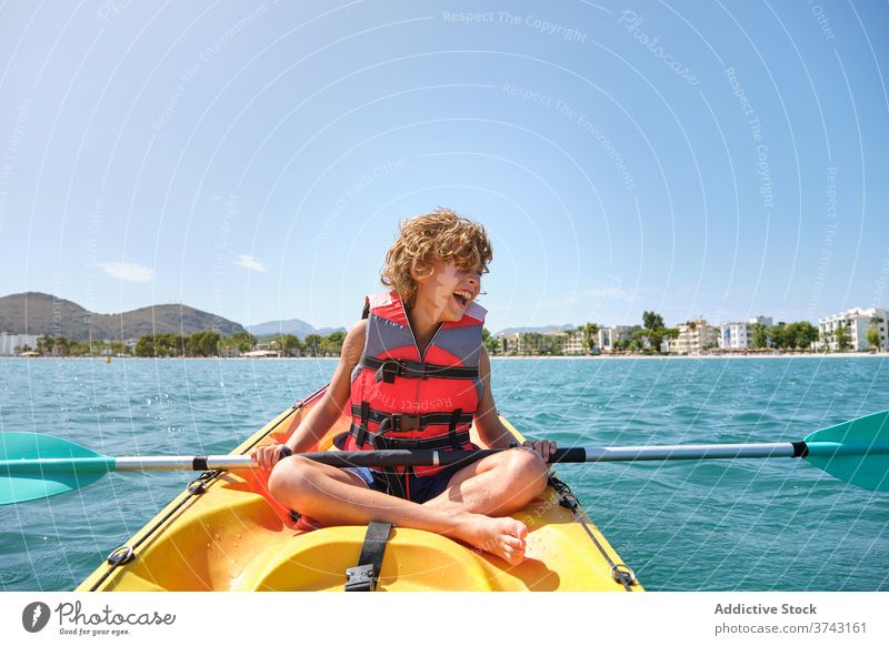 Boy with a life jacket sitting in a kayak in the sea move serious tired safe weekend joyful stop row dangerous pleasure recreation protection action kid outside