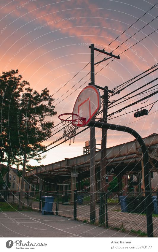 Basketball hoop for in front of train tracks during sunset. basketball hoop chicago court playground urban alley telephone wires