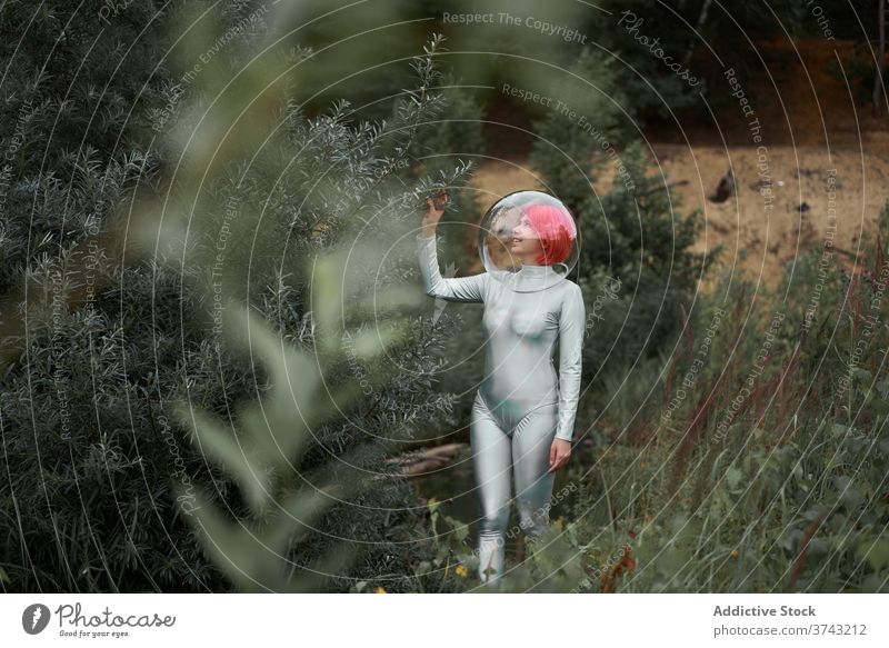 Woman in space suit walking in field woman futuristic astronaut helmet forest nature positive young cosmonaut concept female silver smile observe confident