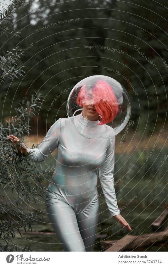 Woman in space suit walking in field woman futuristic astronaut helmet forest nature positive young cosmonaut concept female silver smile observe confident