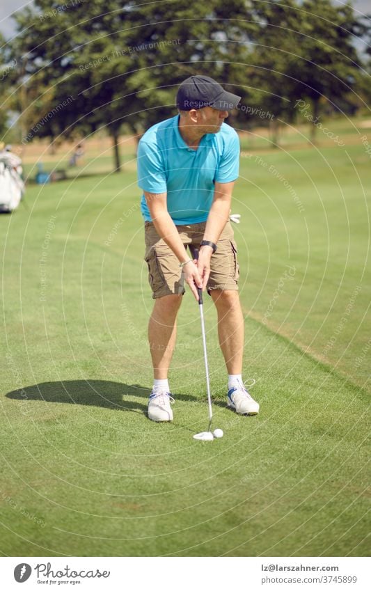 Golfer preparing to play a shot on the fairway lining himself up with the hole before taking his swing in a sporting and active lifestyle concept man male