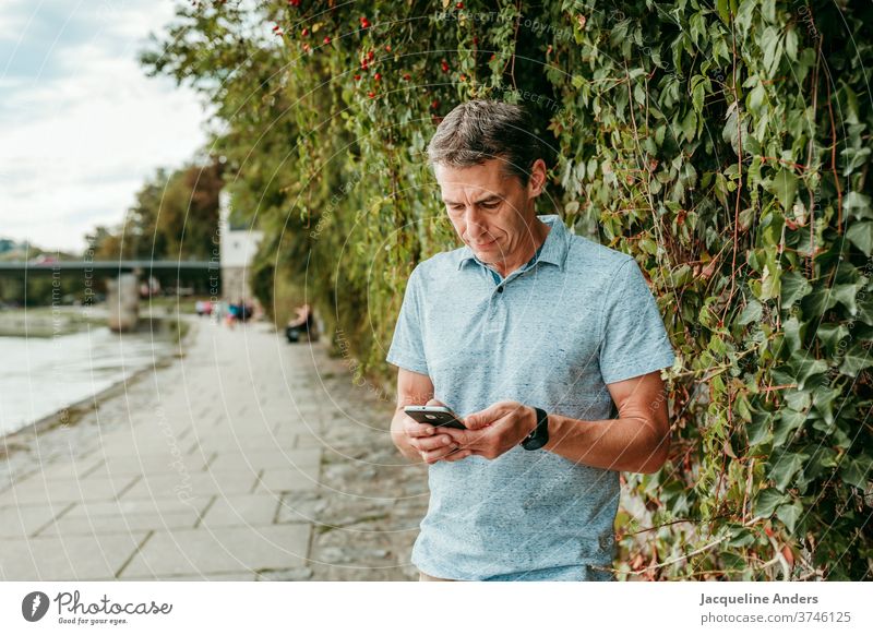 Man looks at his cell phone and texts mobile Telephone Human being more adult smile Mobile Street Technology urban message Copy Space Exterior shot free time