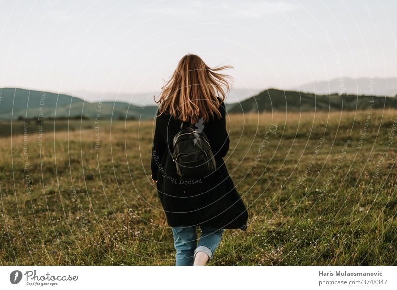 woman with backpack traveling on a windy mountain adventure away from the city background beautiful beauty cheerful female field freedom fresh air fun grass