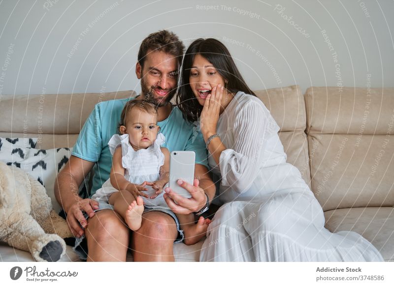 Couple with a toddler on their lap making a selfie with the mobile phone innocence memories lifestyles parenting parents parenthood newborn touch relationship