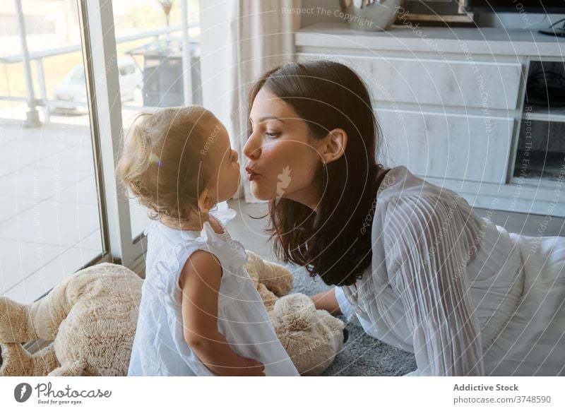 Woman lying on the floor kissing a toddler at home loving innocence tenderness affectionate parenting mum touching feeling infant motherhood togetherness