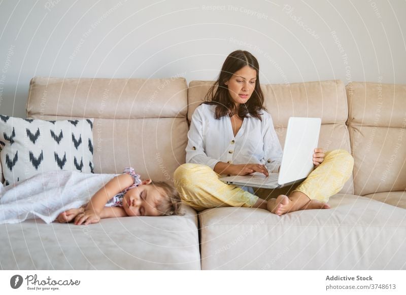 Woman working on the sofa with the laptop while a toddler is sleeping on a side tranquility maternity responsibility tenderness dreaming motherhood newborn