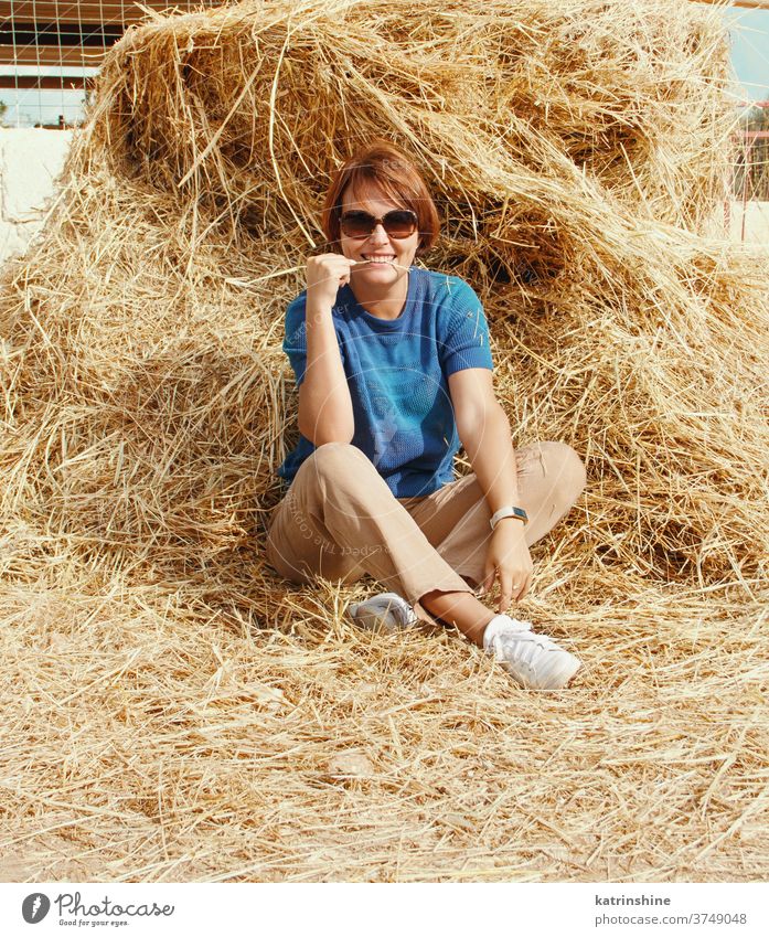Young woman sitting near haystack young girl casual Haystack Relax Caucasian Straw Agriculture Summer Ranch Smiling Adult Rural Harvest Outdoor Nature