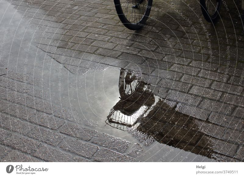 after the rain - detail of a bicycle with bicycle basket on cobblestones is reflected in a puddle reflection Puddle Bicycle Detail Paving stone Light Shadow