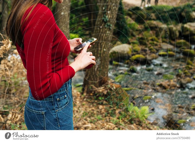 Traveling woman browsing smartphone in forest traveler watching river woods memory nature valle del jerte caceres spain tourist shore flow water amazing
