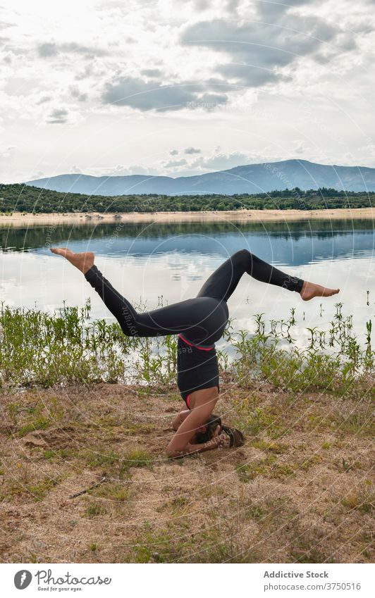 Woman practicing headstand yoga pose near lake woman practice sirsasana balance inversion variation advanced harmony wellness lifestyle female flexible