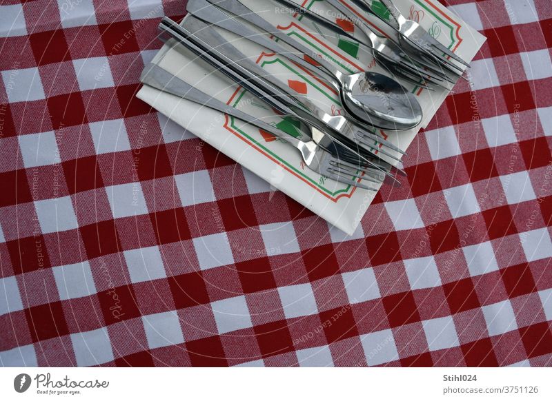 Cutlery lies on napkin on red and white chequered tablecloth Reddish white Checkered Restaurant Napkin coperto Set meal plan Italian pizzeria Knives Fork Spoon
