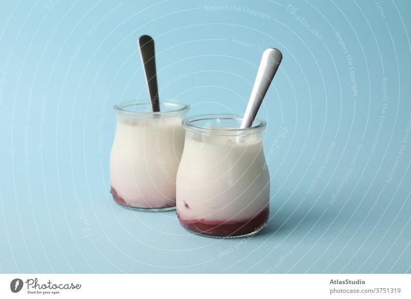 Glass jars of yogurt with spoons on blue background glass natural color sauce concept space snack summer delicious curd homemade flavor wooden protein milk