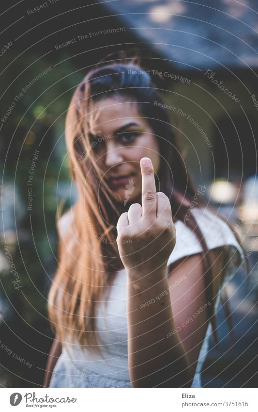 A young woman with long brown hair looks aggressively into the camera and gives the finger Middle finger fuck you Woman Give the finger Aggressive agressive