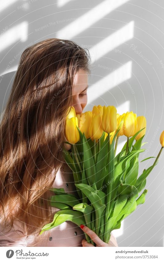 Woman with tulips. Young female with yellow flowers tulip natural portrait lifestyle near white background. march 8 young woman girl beautiful nature beauty