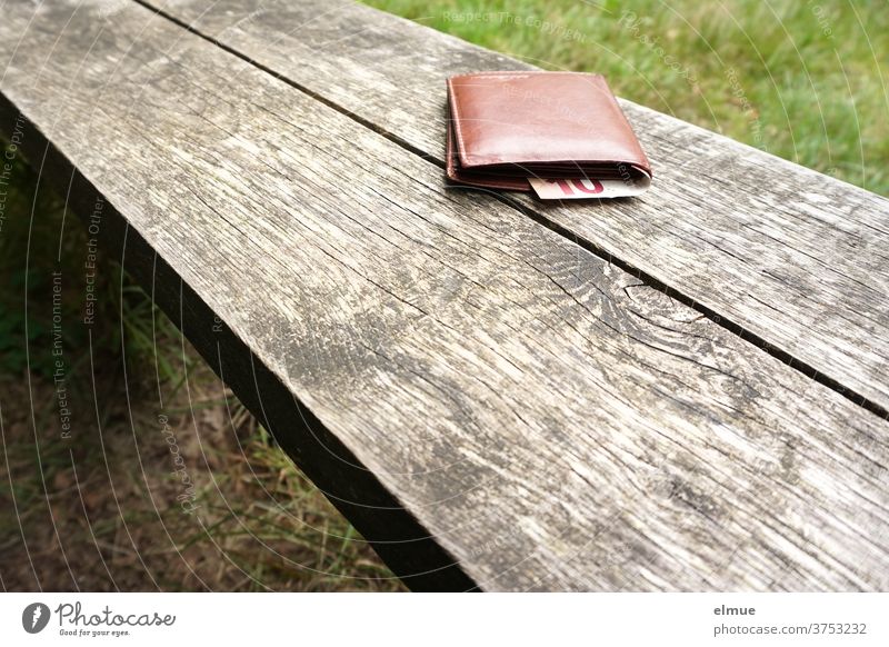Lost property - a brown wallet with a visible 10-euro note lies on a wooden bench in the green Money purse Wallet Doomed leave it at Bench portmonee