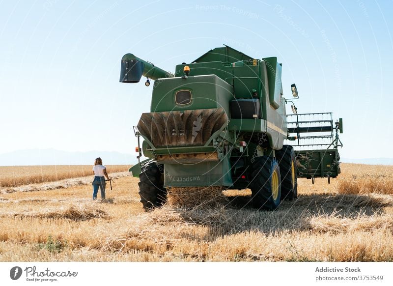 Woman near combine harvester in field woman machine agriculture wheat farmer equipment grain female industry rural huge nature summer plant organic growth
