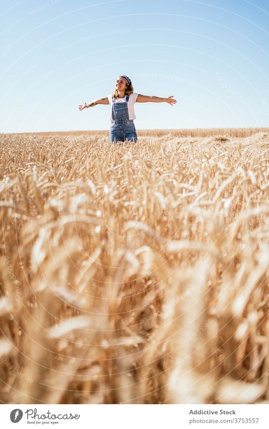 Carefree woman in field in summer carefree countryside freedom enjoy delight wheat golden female nature denim overall cheerful vacation meadow sky positive