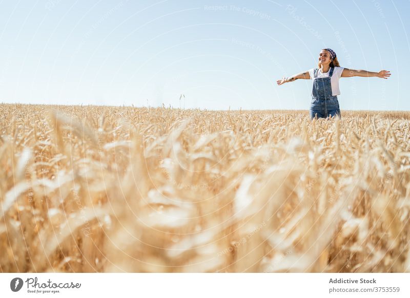 Carefree woman in field in summer carefree countryside freedom enjoy delight wheat golden female nature denim overall cheerful vacation meadow sky positive