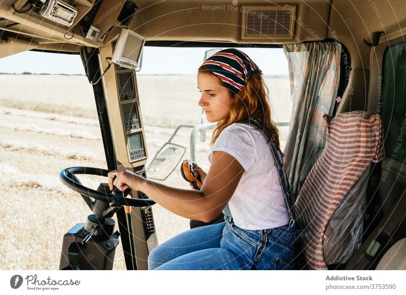 Focused woman operating agricultural machine farm combine harvest operate collect season field agriculture female wheat rural job transport vehicle equipment
