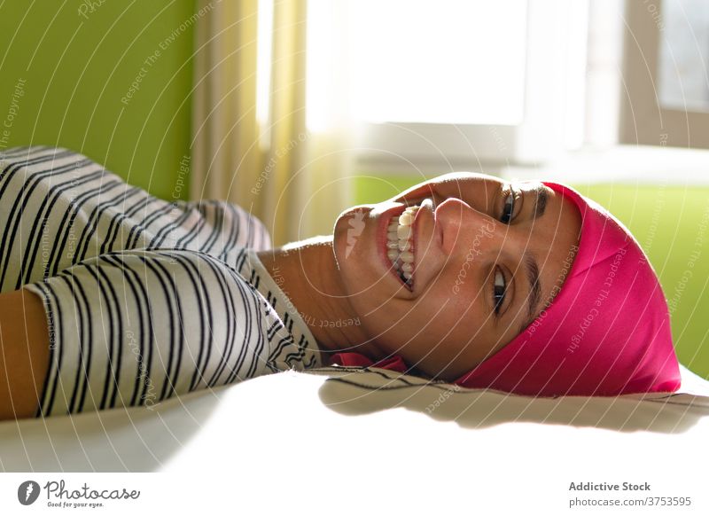 Content woman with cancer lying on bed hope smile headscarf survive oncology home female delight bald joy optimist disease illness diagnosis faith aware