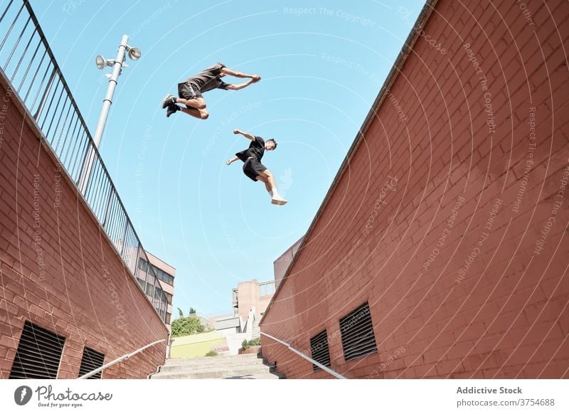 Men jumping over stairway in city parkour stunt trick men together urban extreme danger hobby courage active activity professional brave adrenalin cool energy