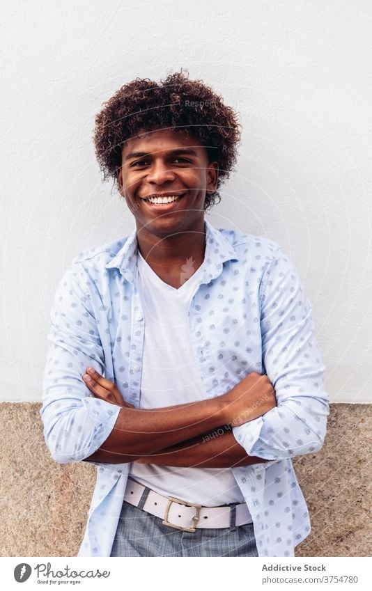 Happy man in stylish wear in city style trendy modern street posture building wall male ethnic black african american appearance hairstyle afro outfit stone