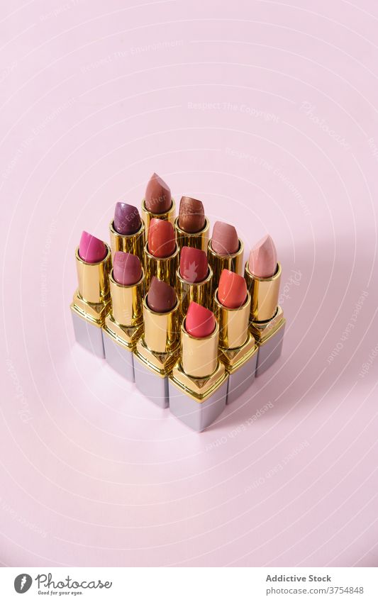 Set of varicolored lipsticks on pink background collection makeup product arrangement row set matte beauty professional assorted line decorative bright creative