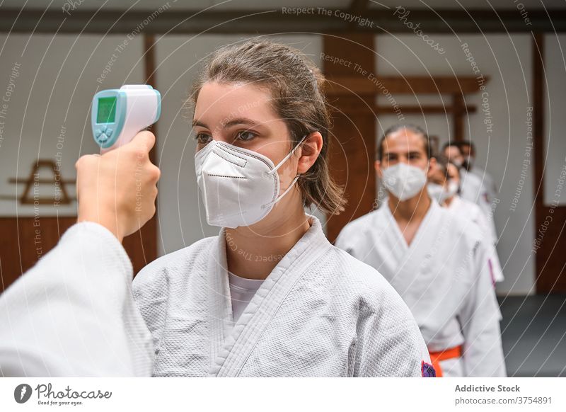 People wearing masks and a kimono taking the covid temperature test in a gym scan students seminar staff trainer fever learn pandemic practice corona epidemic