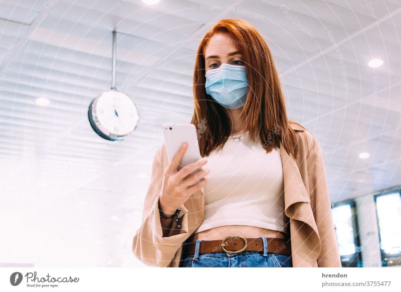 woman with a mask using her smartphone at the train station public journey tourist trip traveling voyage economy virus coronavirus epidemic pandemic protection