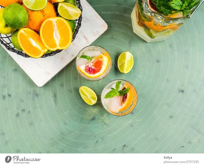 Fresh summer citrus drink with ice on green water cocktail lemonade detox mocktail blood orange fruit flat lay top view lime juice mint soda infused sweet