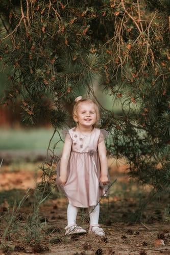 little cute girl have fun under tree with cones on a sunny spring day young kid happiness beautiful caucasian cheerful child childhood green happy lifestyle