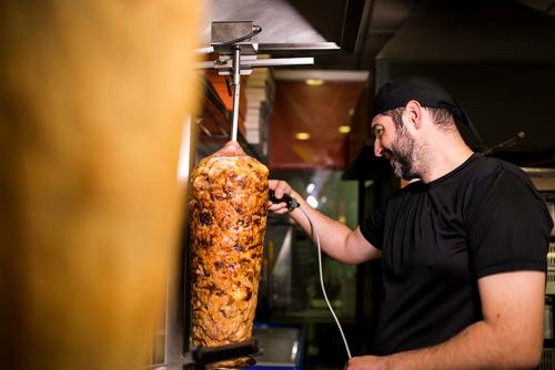 Bearded man preparing kebab meat in pizza bar. turkish adult person people lifestyle attractive men male bearded store junk food business portion night smile