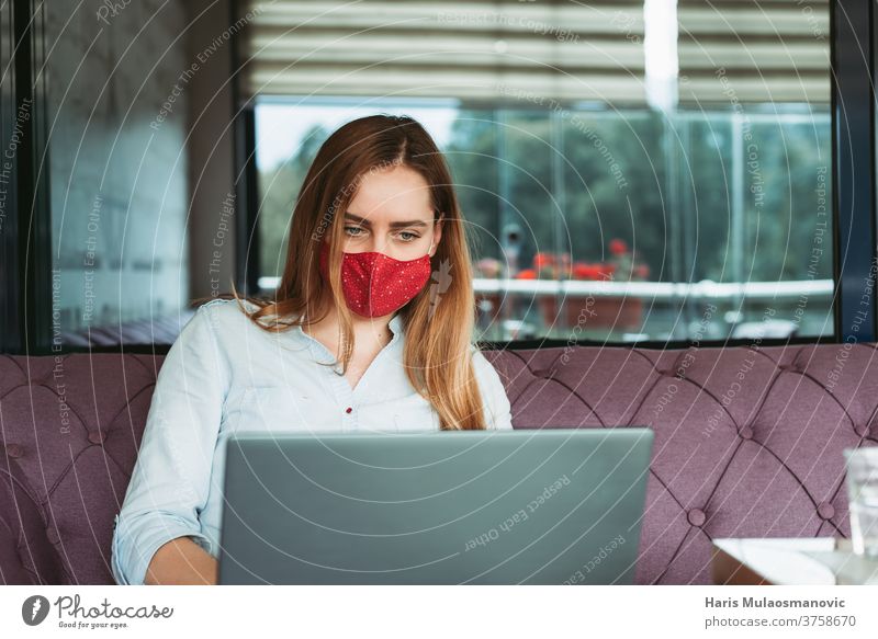 Woman freelancer with face mask working on laptop in coffee shop adult attractive beautiful business businesswoman cafe communication coronavirus