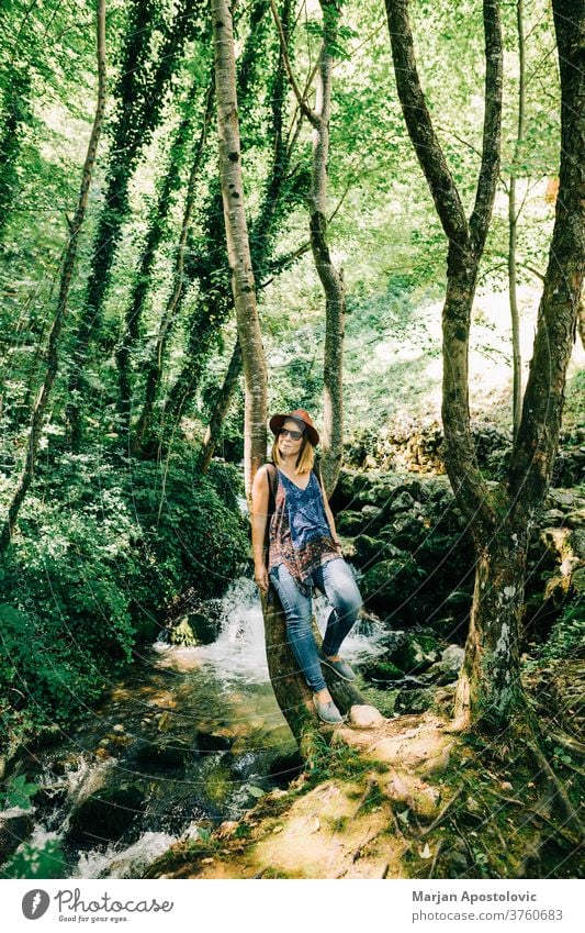 Young woman by the tree in the forest adult adventure adventurer beautiful casual caucasian enjoying environment explore female free freedom fresh green