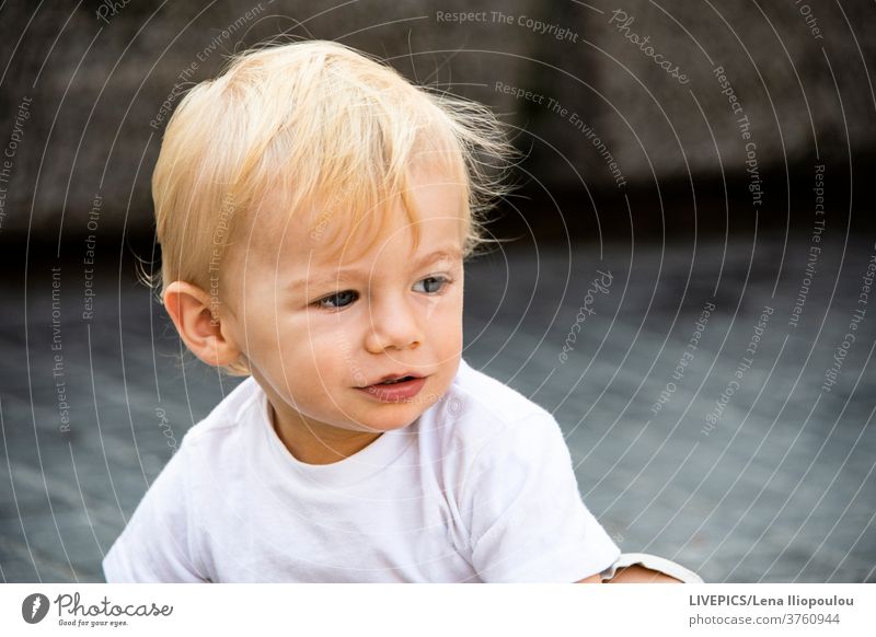 portrait of a blond young boy baby background body part charming child close-up copy space day daylight expression face guy hair head kid looking away
