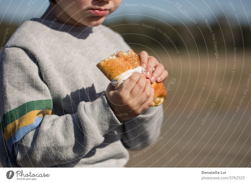 Child eats sandwich outdoor appetite appetizer boy bread breakfast calzone carbohydrate caucasian child closeup delicious eating fast-food fastfood holding junk