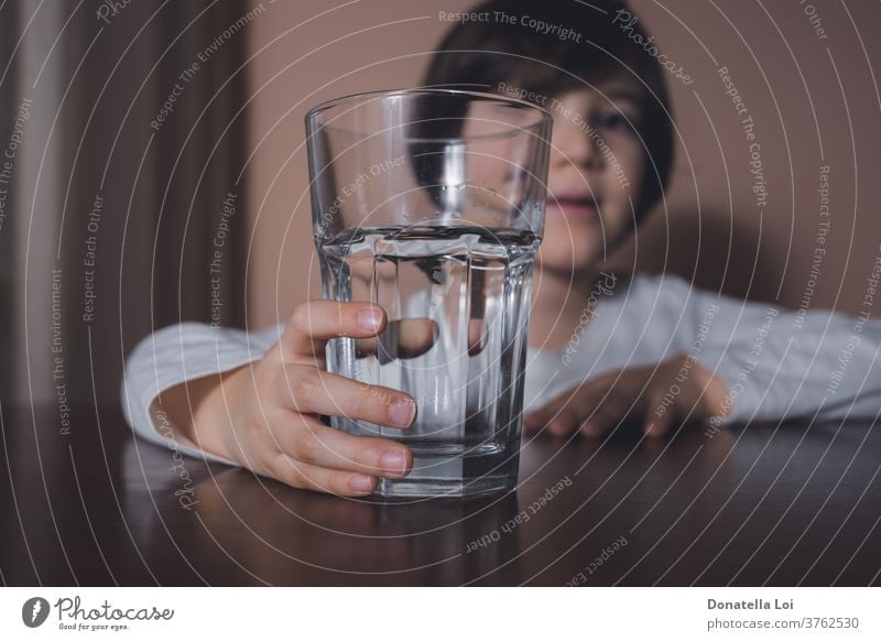 Child with water glass beverage big boy caucasian child childhood clean closeup cute daily diet drink eyes face finger fresh hand health healthy hold home